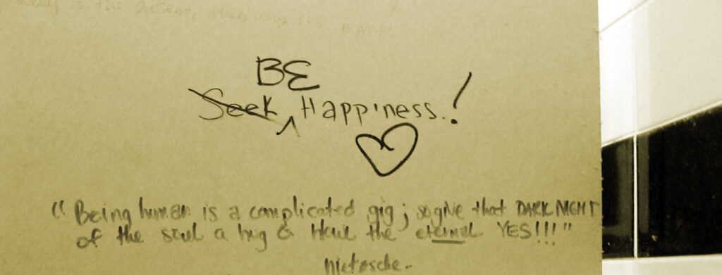 A message on a wall that read seek happiness, but now reads, "be happiness."